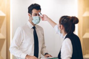 Hotel worker scanning temperature of fellow hotel employee